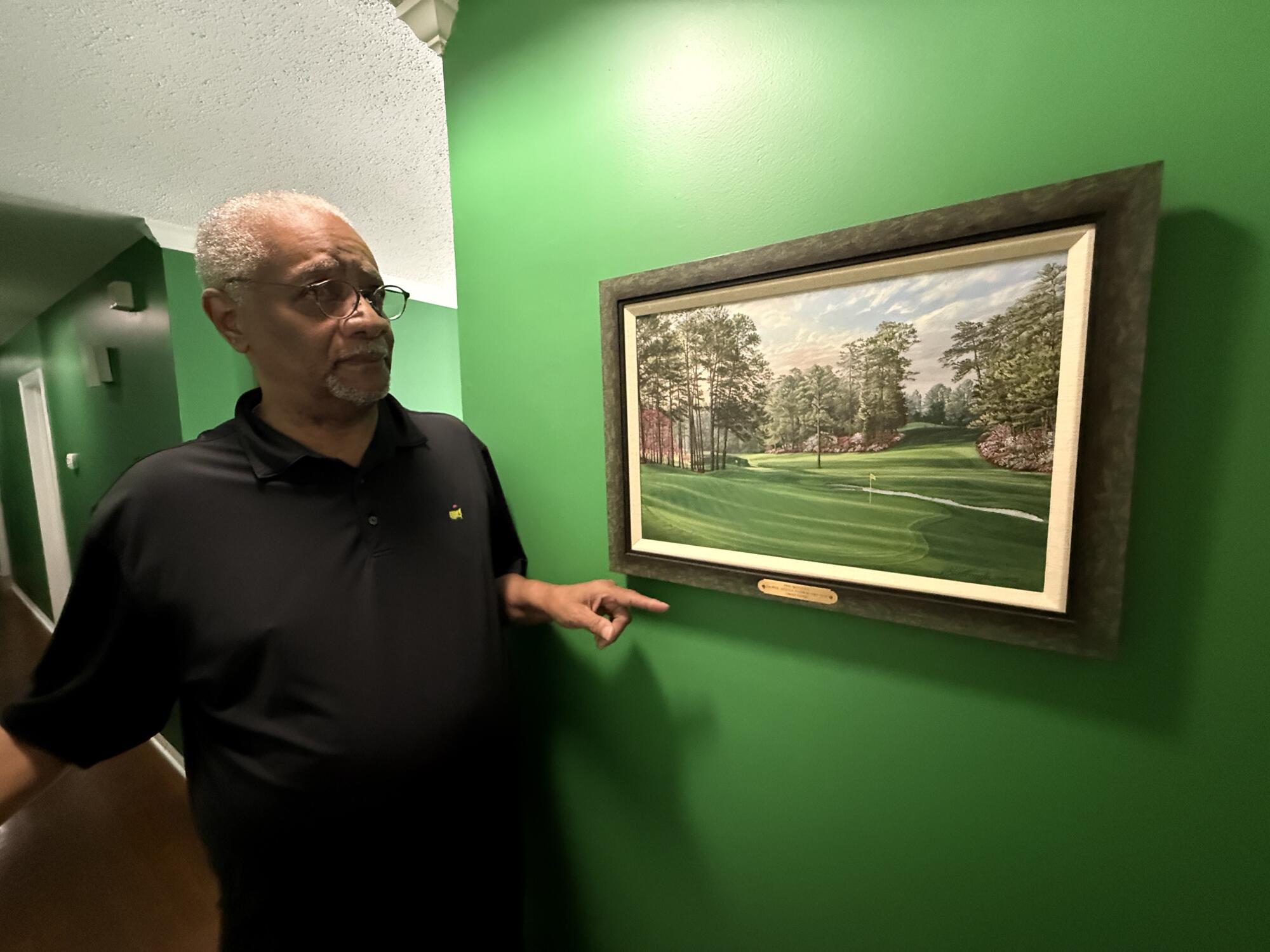 Lawrence Bennett, longtime chauffeur at Augusta National, points to a painting of the course in his home.