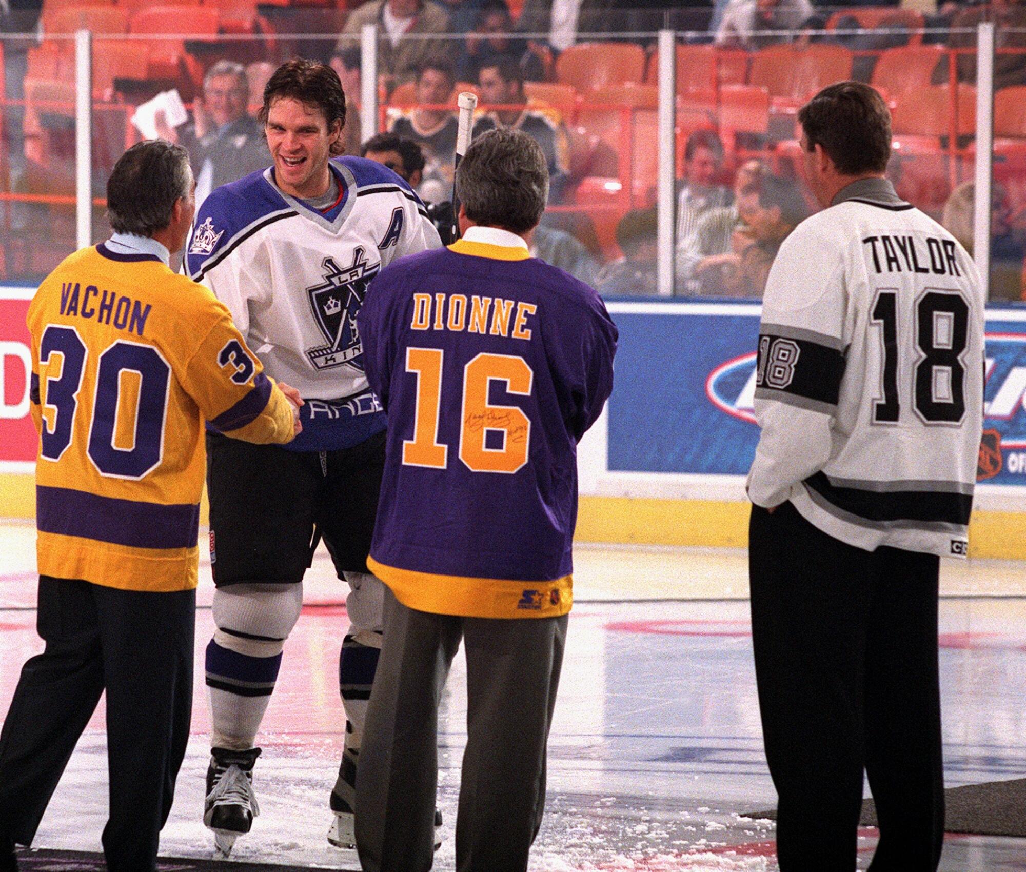Luc Robitaille shakes hands with Rogie Vachon as Kings greats Marcel Dionne and Dave Taylor look on.