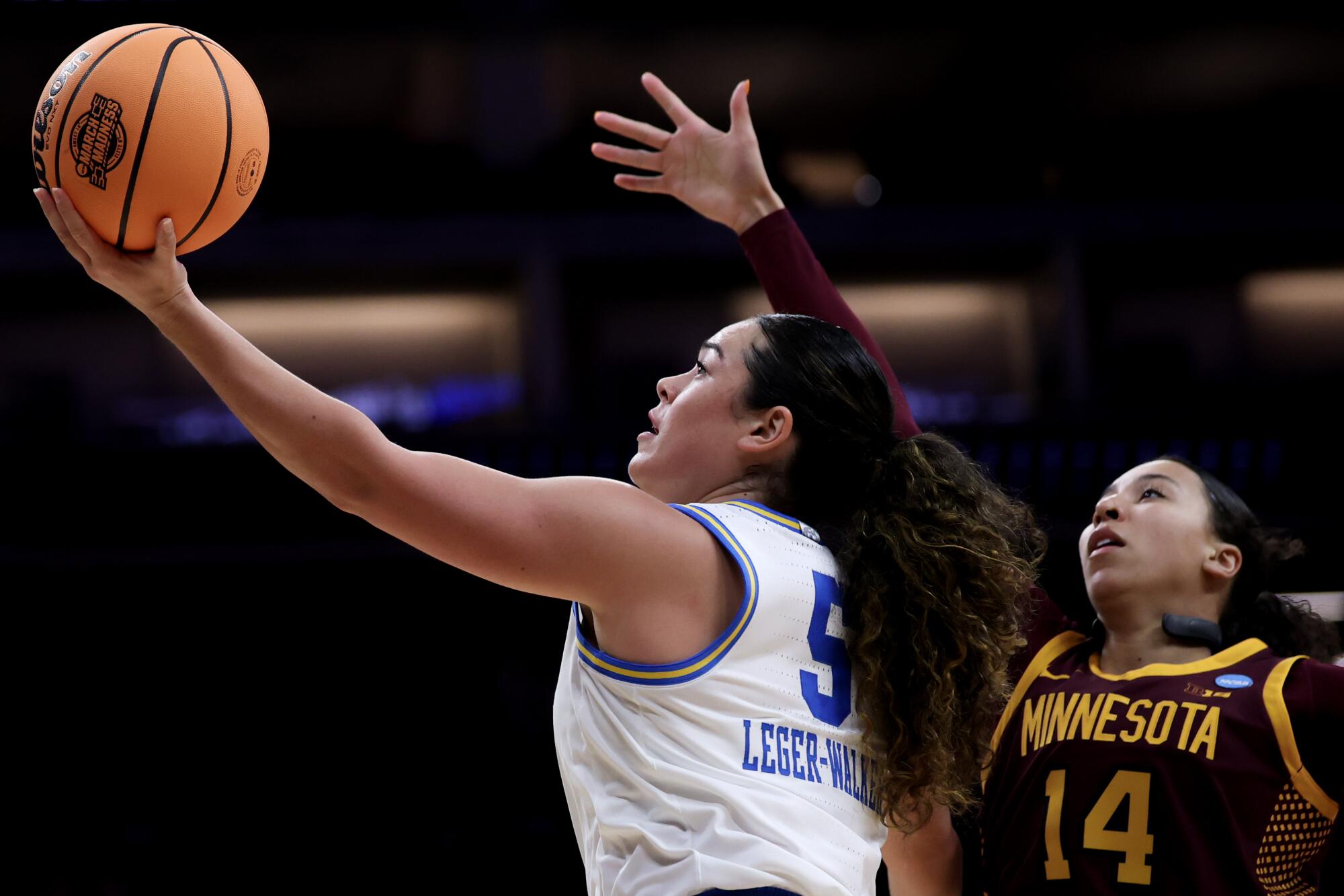 UCLA guard Charlisse Leger-Walker slips past Minnesota guard Tori McKinney and scores on March 27 in Sacramento.