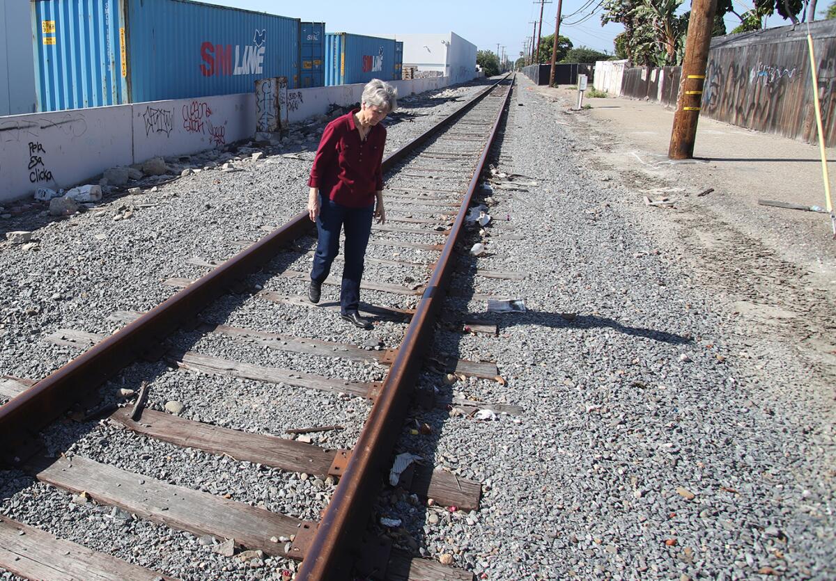 Kathy Stephens of Huntington Beach walks on train tracks behind her property on Rhone Lane on Tuesday. 