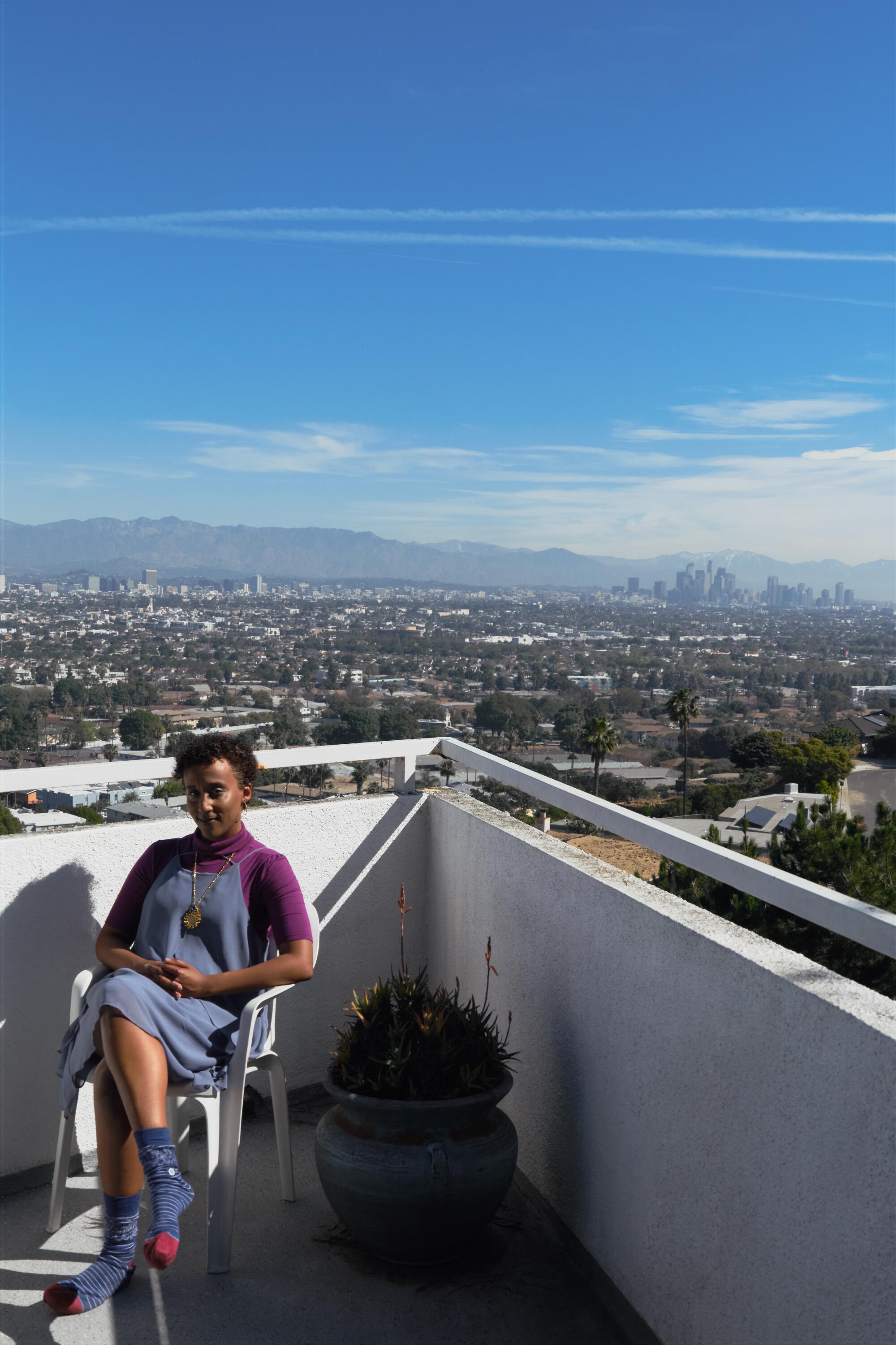 Felema Ye sitting on her outside deck with a beautiful view of Los Angeles. 