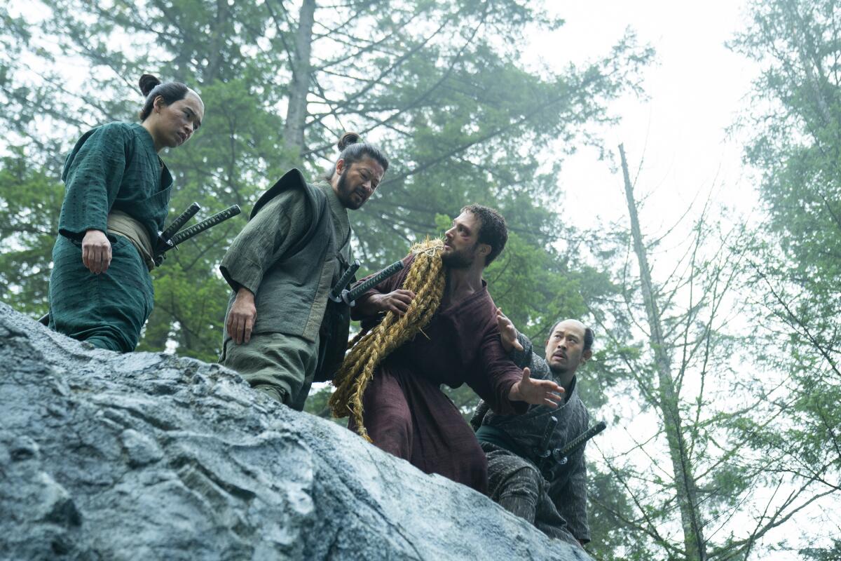 Four men stand on the edge of a rock cliff in a still from the show "Shogun."