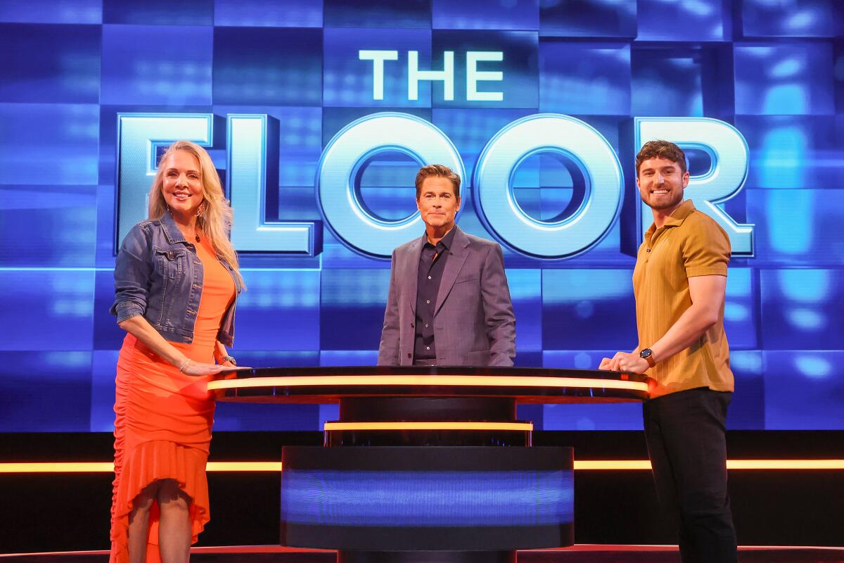 Rob Lowe stands with two contestants on the game show "The Floor," which shoots in Ireland.