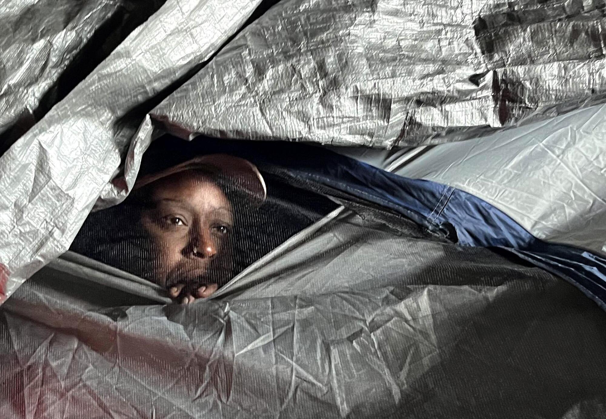 Tiffany Crear peers out from her makeshift tent under the 110 Freeway in Los Angeles.