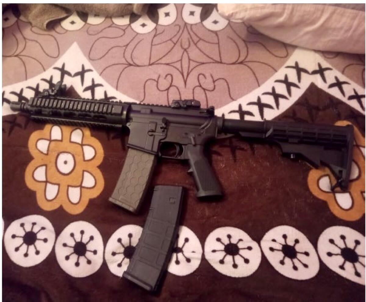 An assault weapon and spare magazine against a printed brown and beige background