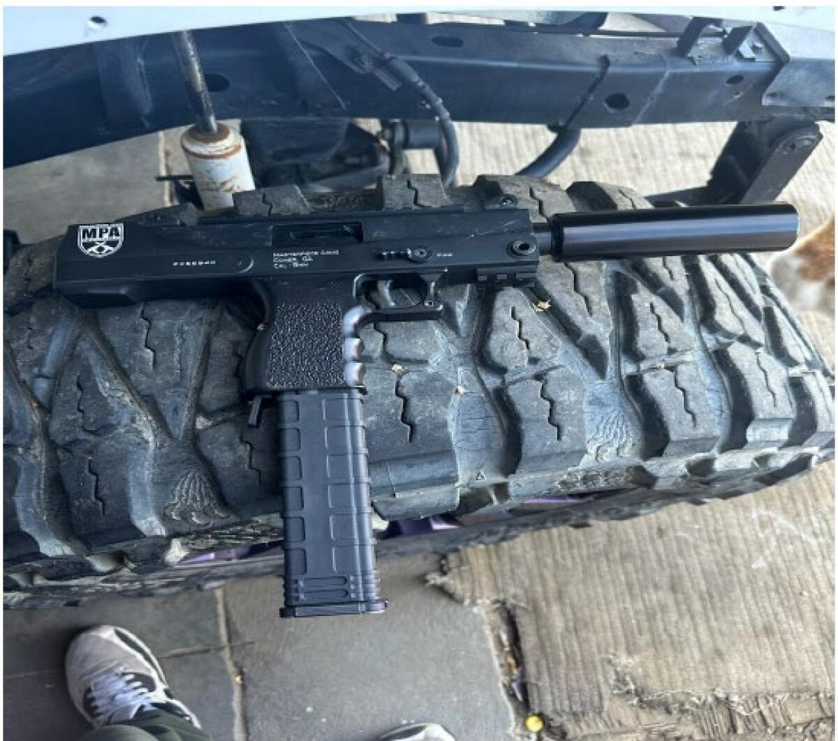 A photo of an assault weapon resting on a large tire