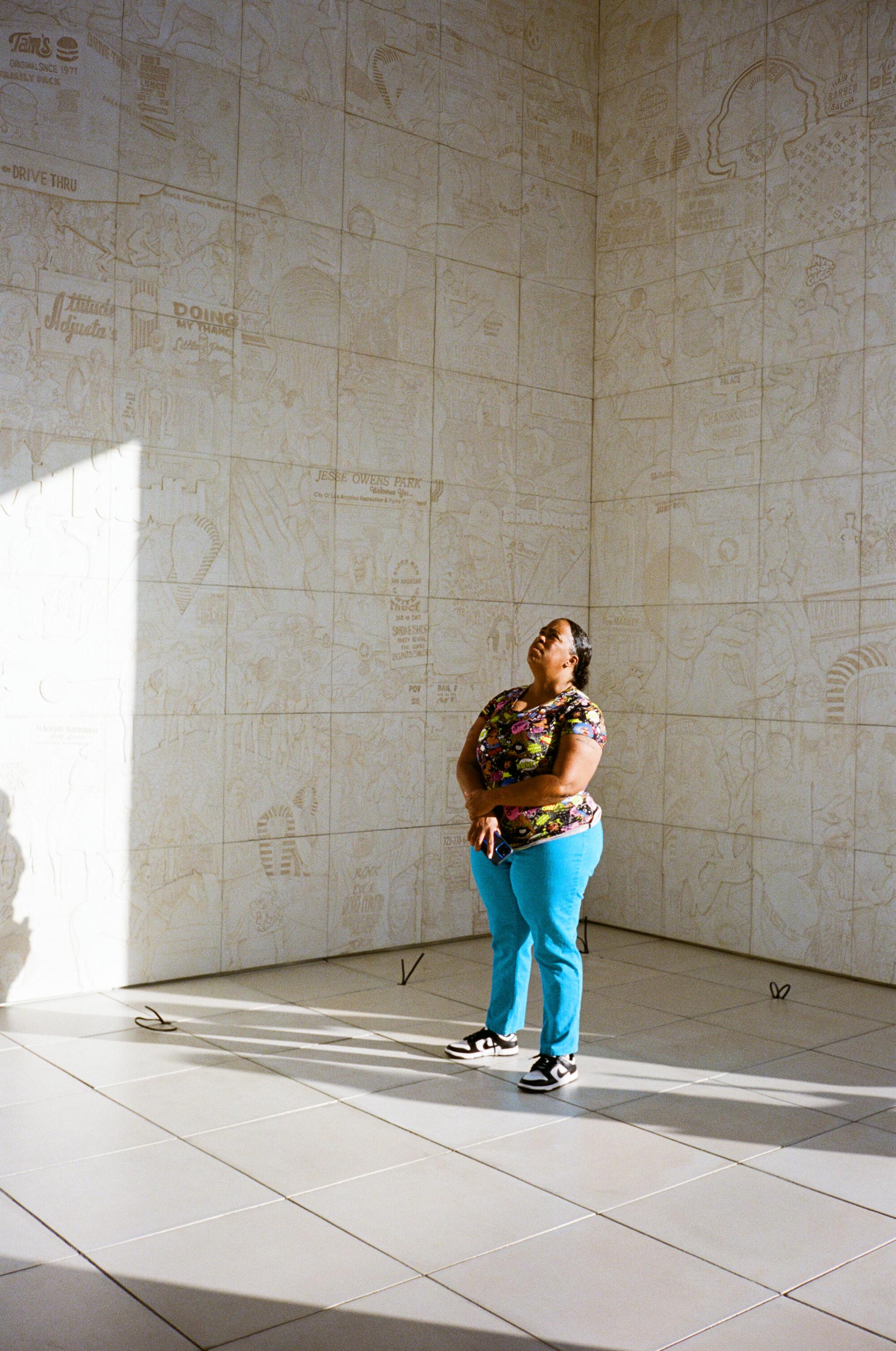 Robin Daniels, co-founder of Sisters of Watts, looking up at the carved reliefs in "sister dreamer."