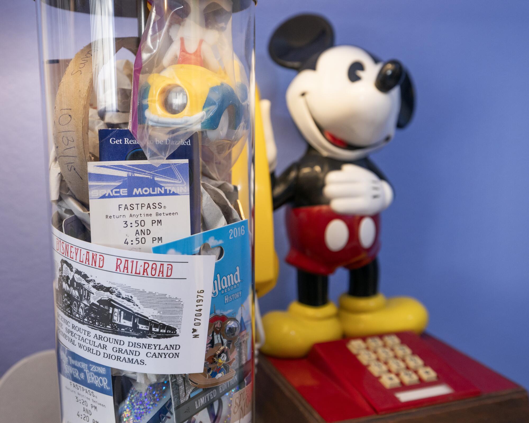A bedside lamp is filled with Disney ticket stubs next to a Mickey Mouse telephone.