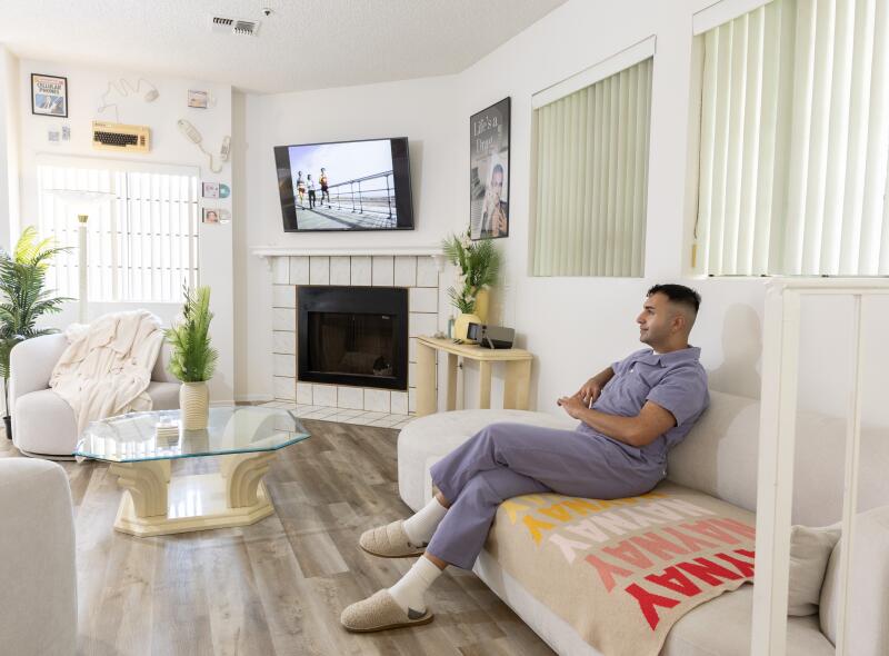 Brandon Shahniani sits in his living room. 