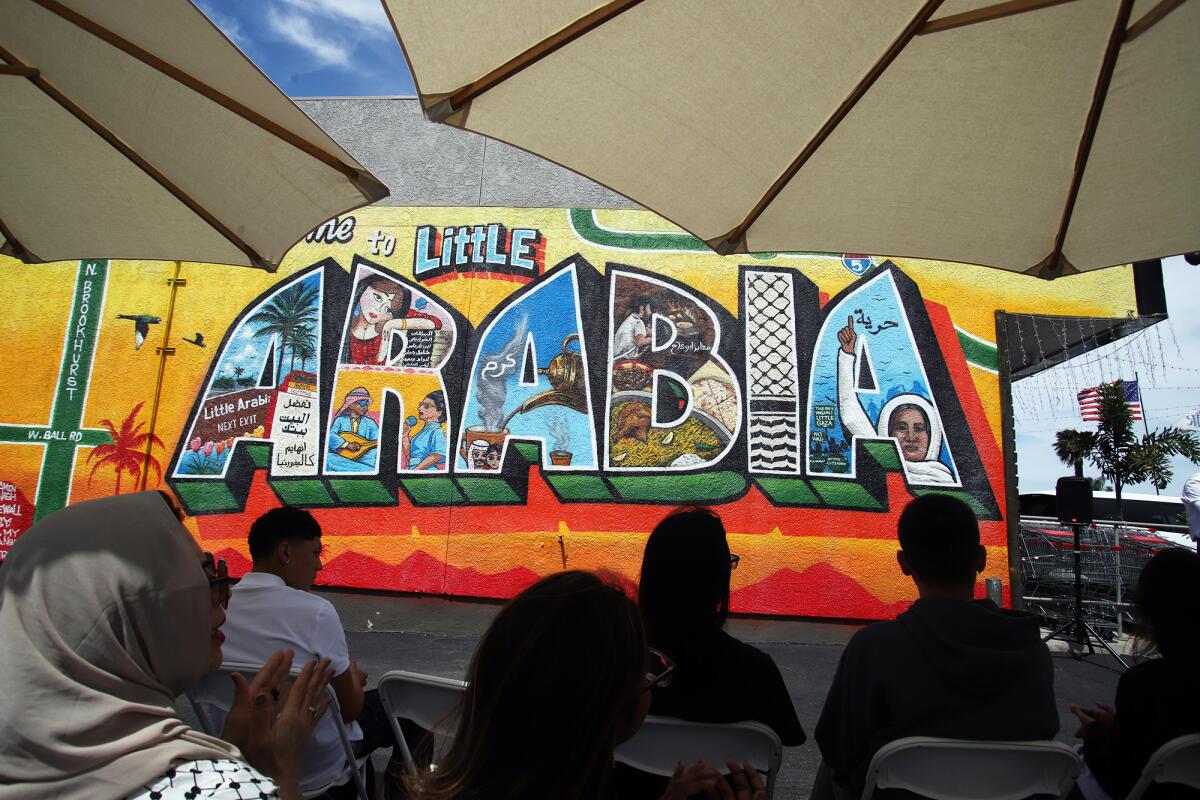 Guests sit in the shade during the "Welcome to Little Arabia" dedication ceremony at Al-Karmel Meat Market In Little Arabia.