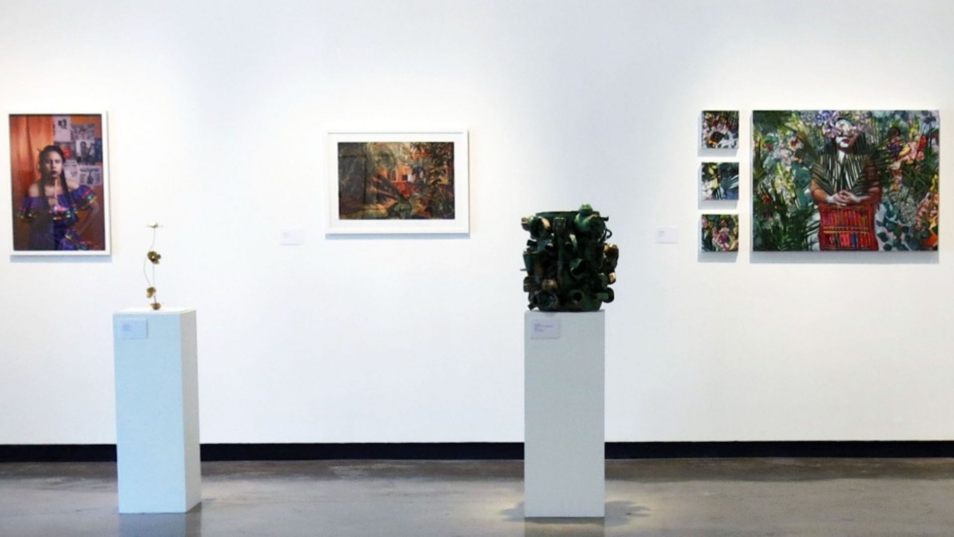 Art gallery wall displays vibrant paintings and sculptures on white pedestals.