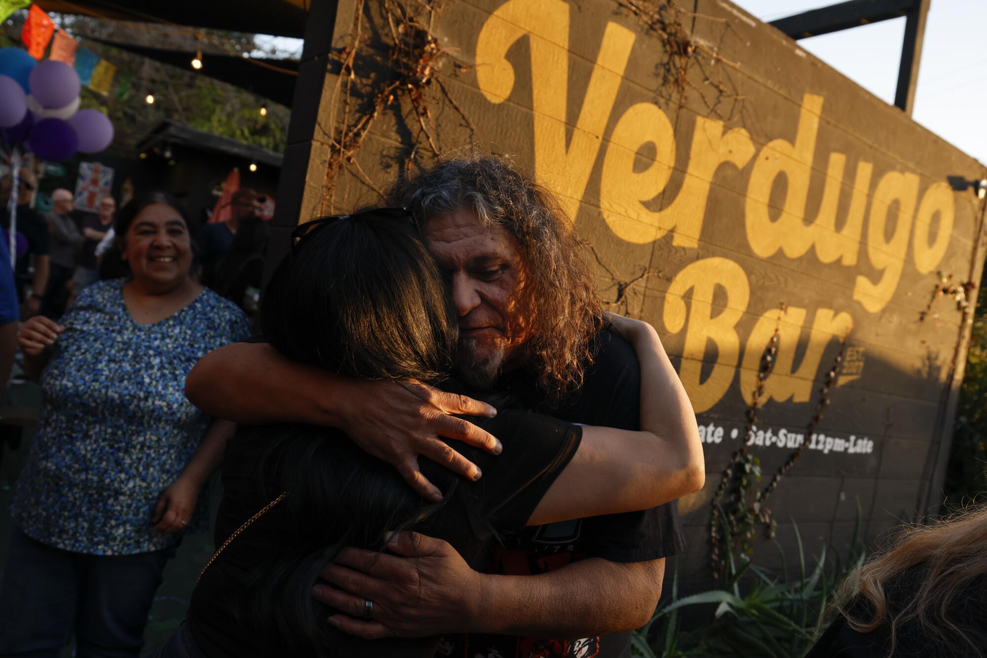 Ayala (center) hugs a friend at his retirement party