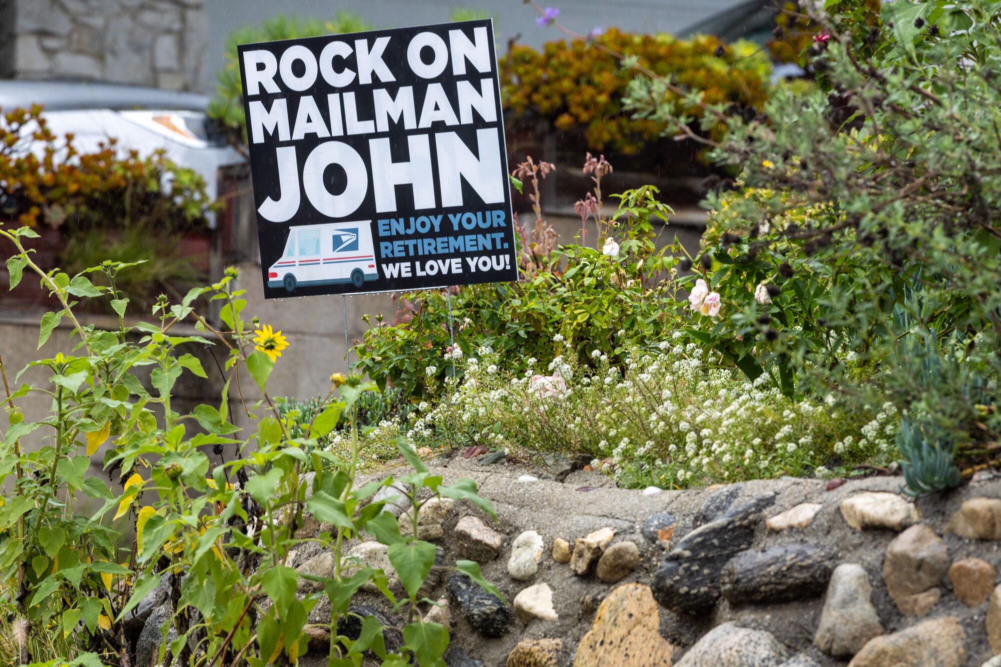 A yard sign says "Rock on Mailman John" 