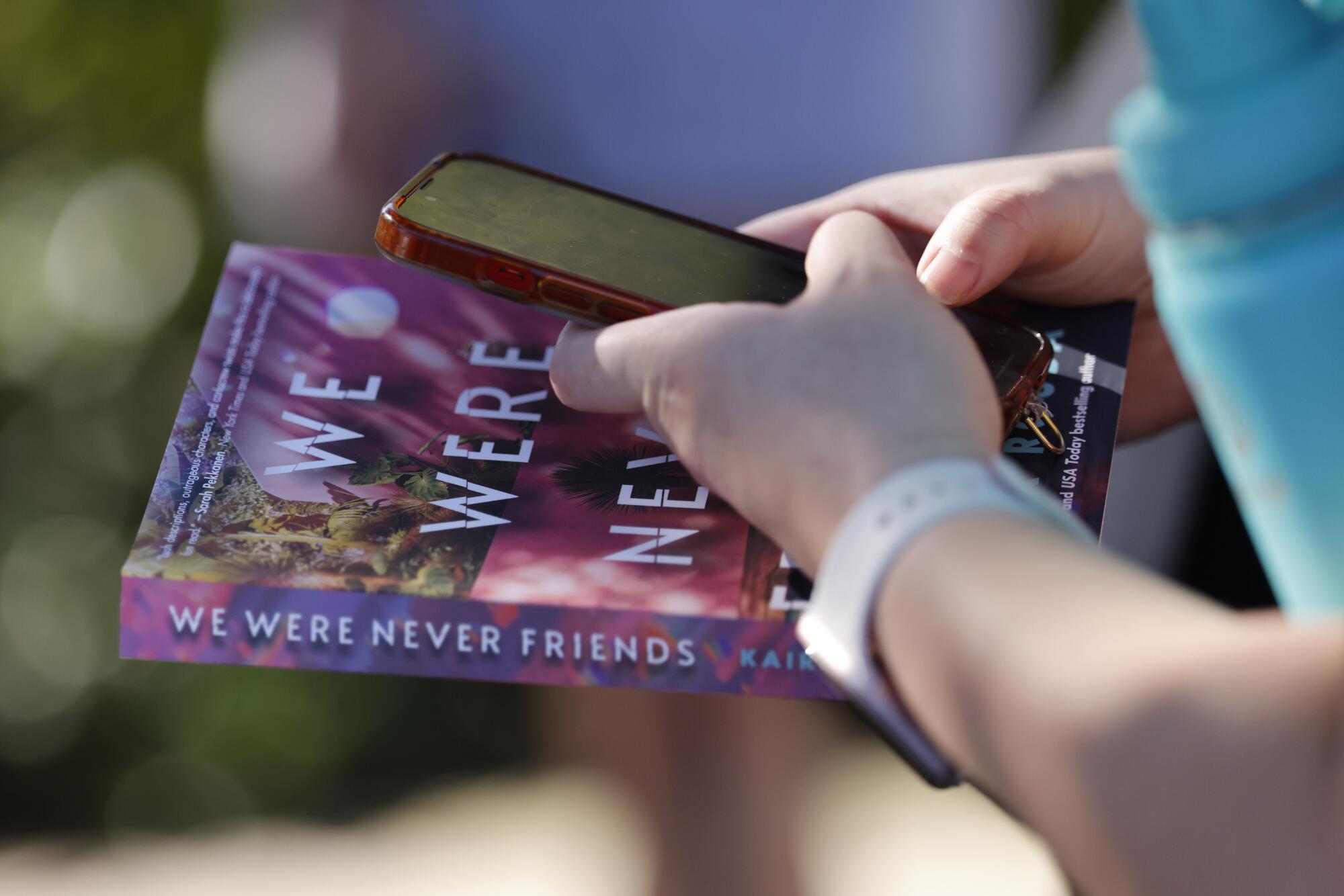 A person holds a book outside 