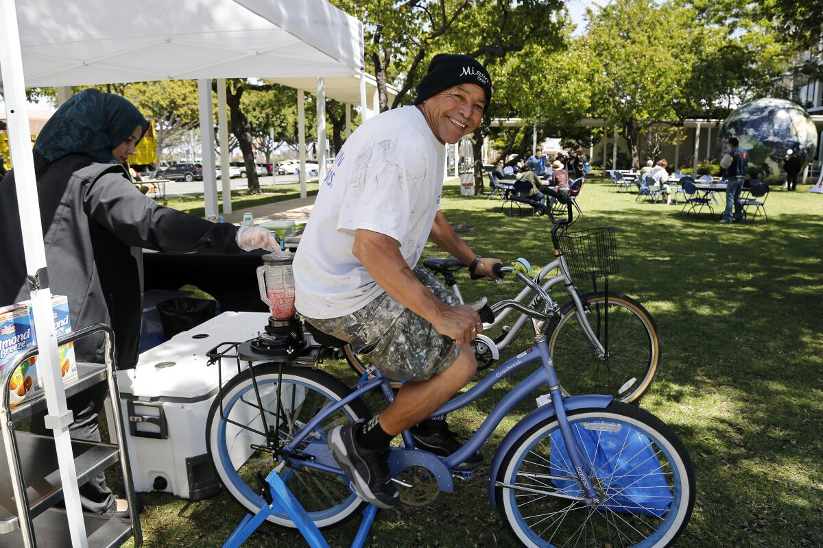 Costa Mesa resident Guillermo Espinoza, 55, right, pedals a bicycle during Costa Mesa's Earth Day Festival..