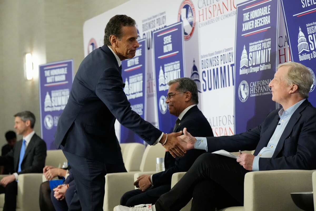 A standing man shakes hands with a seated man.