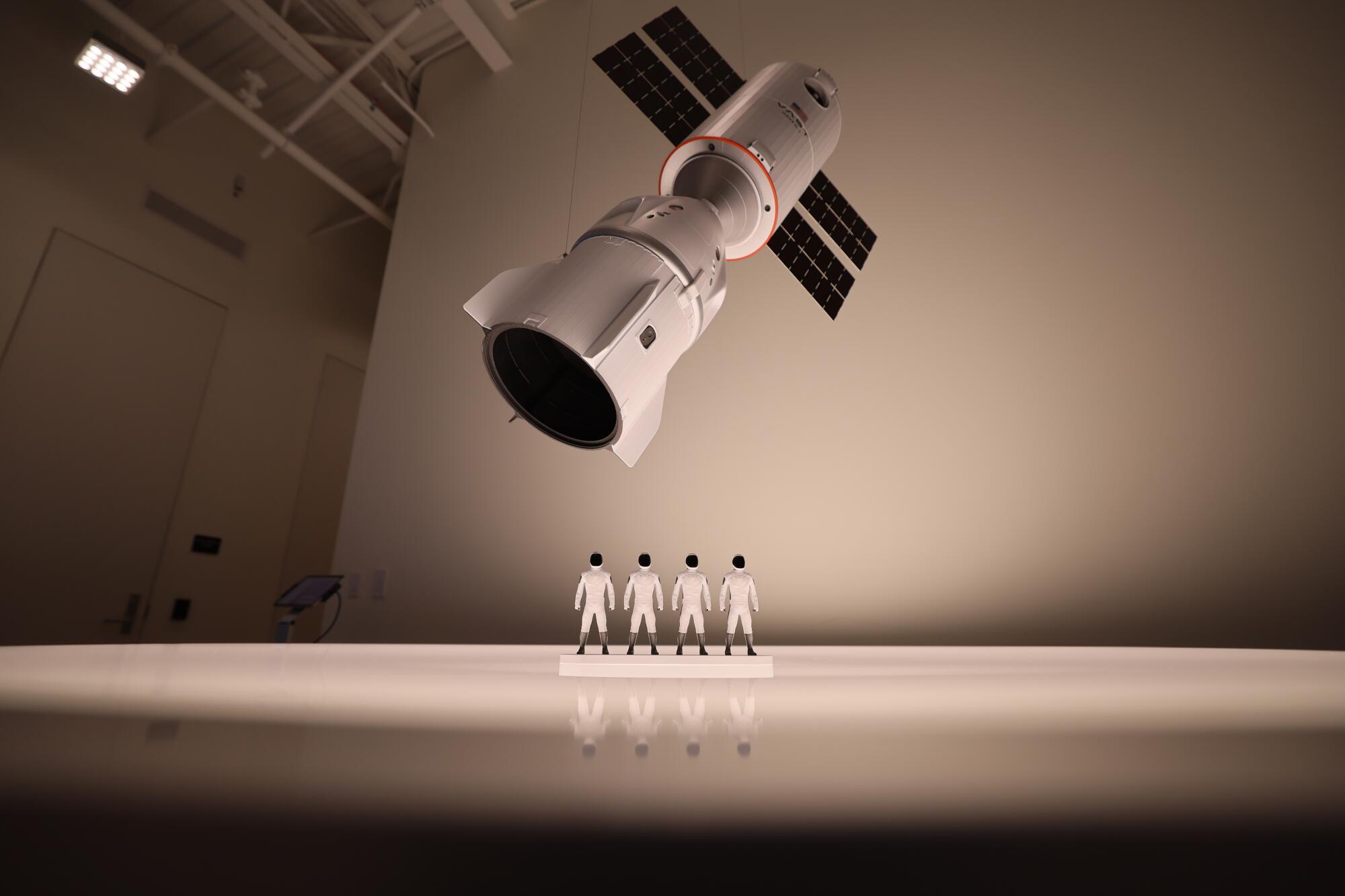 Four mannequins under a model of a space station.