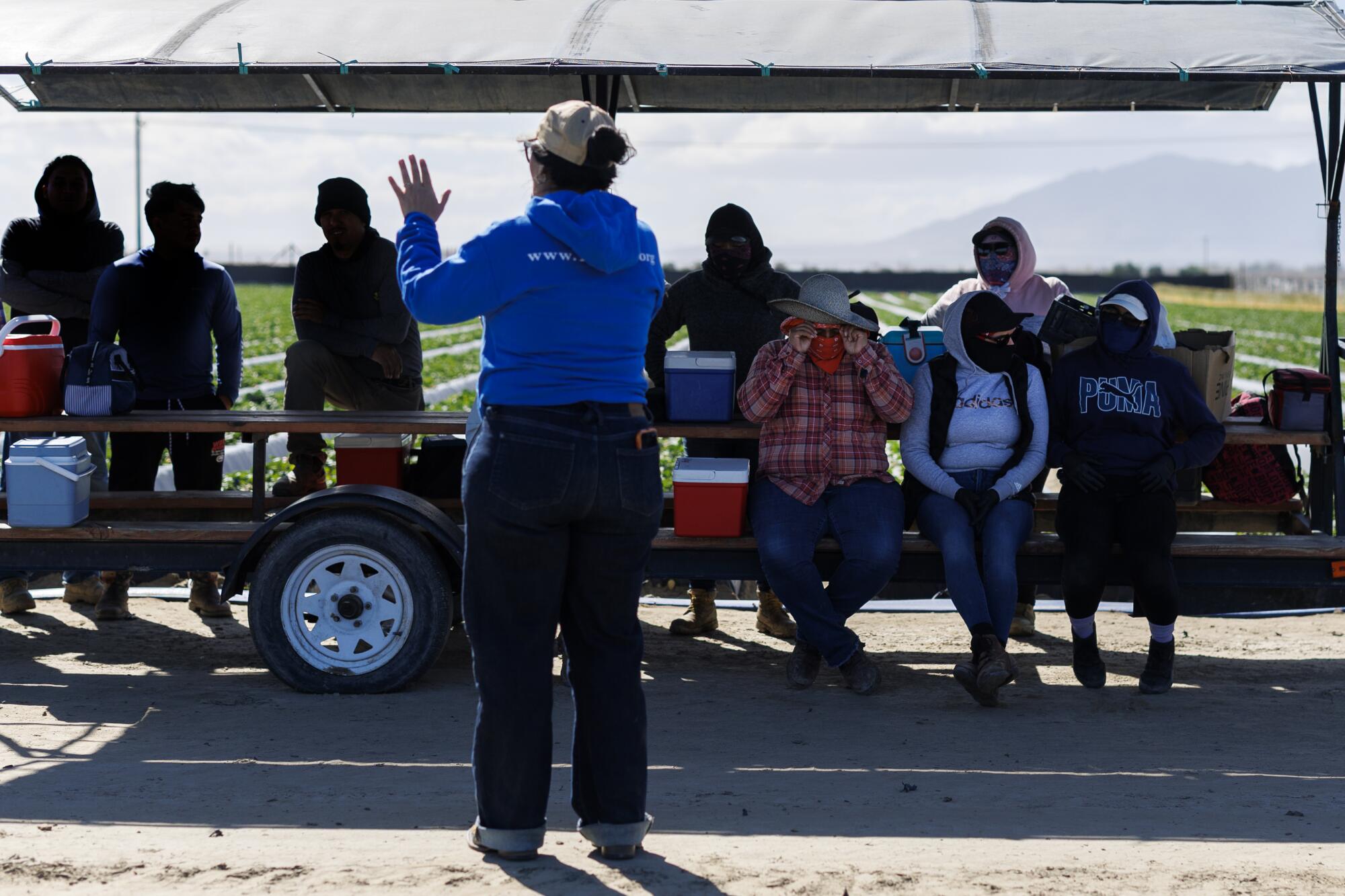 Farmworkers take a break from picking strawberries to listen to a speaker.