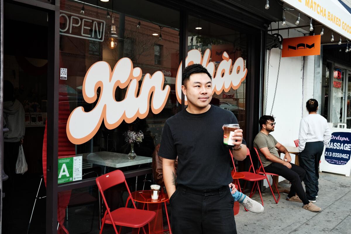 Nam Coffee owner Vince Nguyen holds a drinks and stands outside his new Chinatown coffee shop