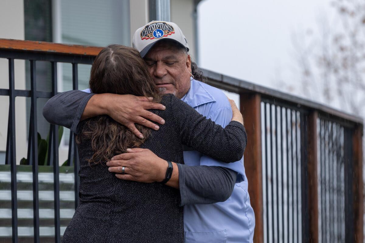 USPS postal carrier John Ayala embraces Los Angeles resident Lori C Murphy during his last shift in Mt. Washington 