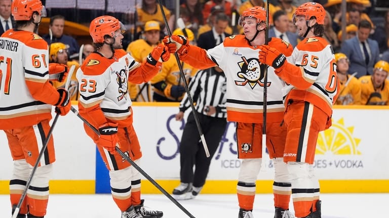 Anaheim Ducks defenseman Jackson LaCombe, second from right, celebrates his...