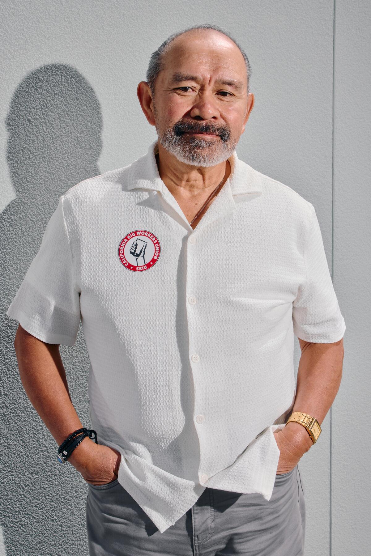 A man stands for a portrait in a white button up shirt