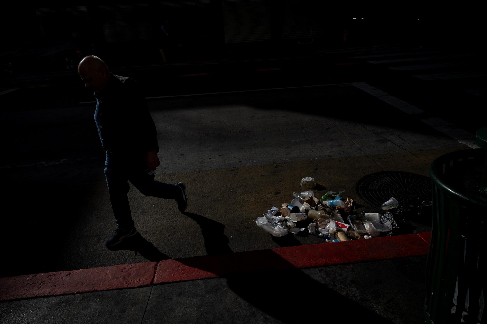 A man walks past a pile of trash left on the street in the historic district.