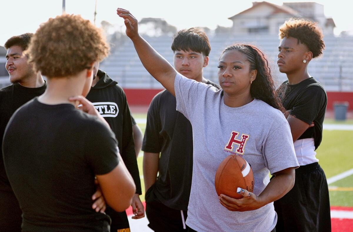 Hawthorne High football coach Jazmin Gamble holds her right hand up as she calls for her players to huddle at practice.