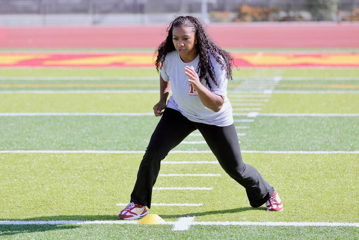 Hawthorne High football coach Jazmin Gamble shows her players how to run a drill during practice.