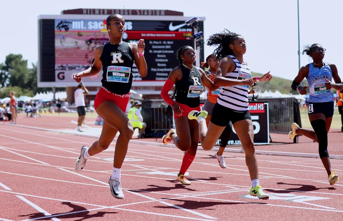 Rosary’s Justine Wilson (left) wins the Invitational 100-meter dash by three hundredths of a second.