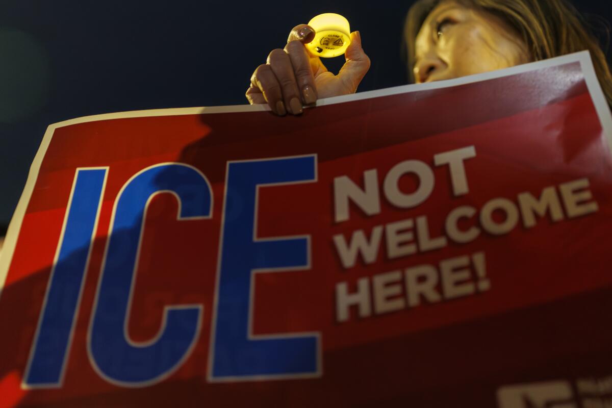 A woman holds a "ICE not welcome here!" sign at a vigil in San Pedro in January.