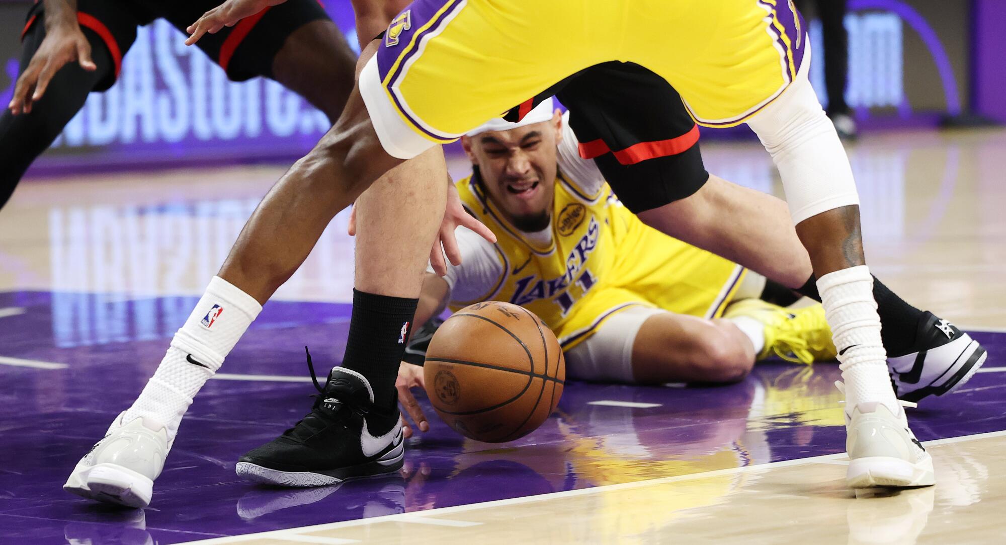 Lakers center Jaxson Hayes, sprawled on the court, reaches for a loose ball in the paint during the first quarter.