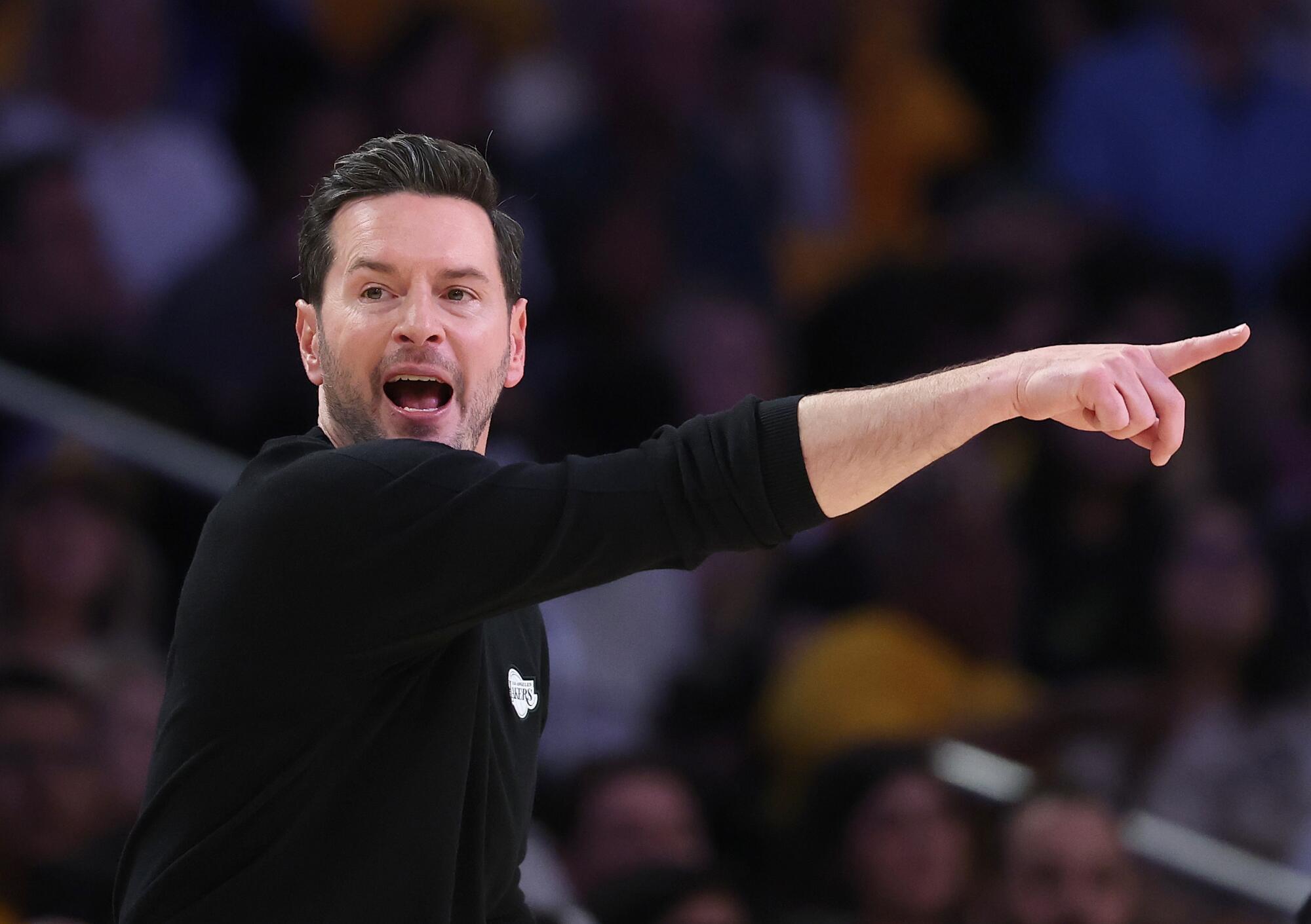Lakers coach JJ Redick points with his right hand to his left while giving instructions to his players on the court in Game 1