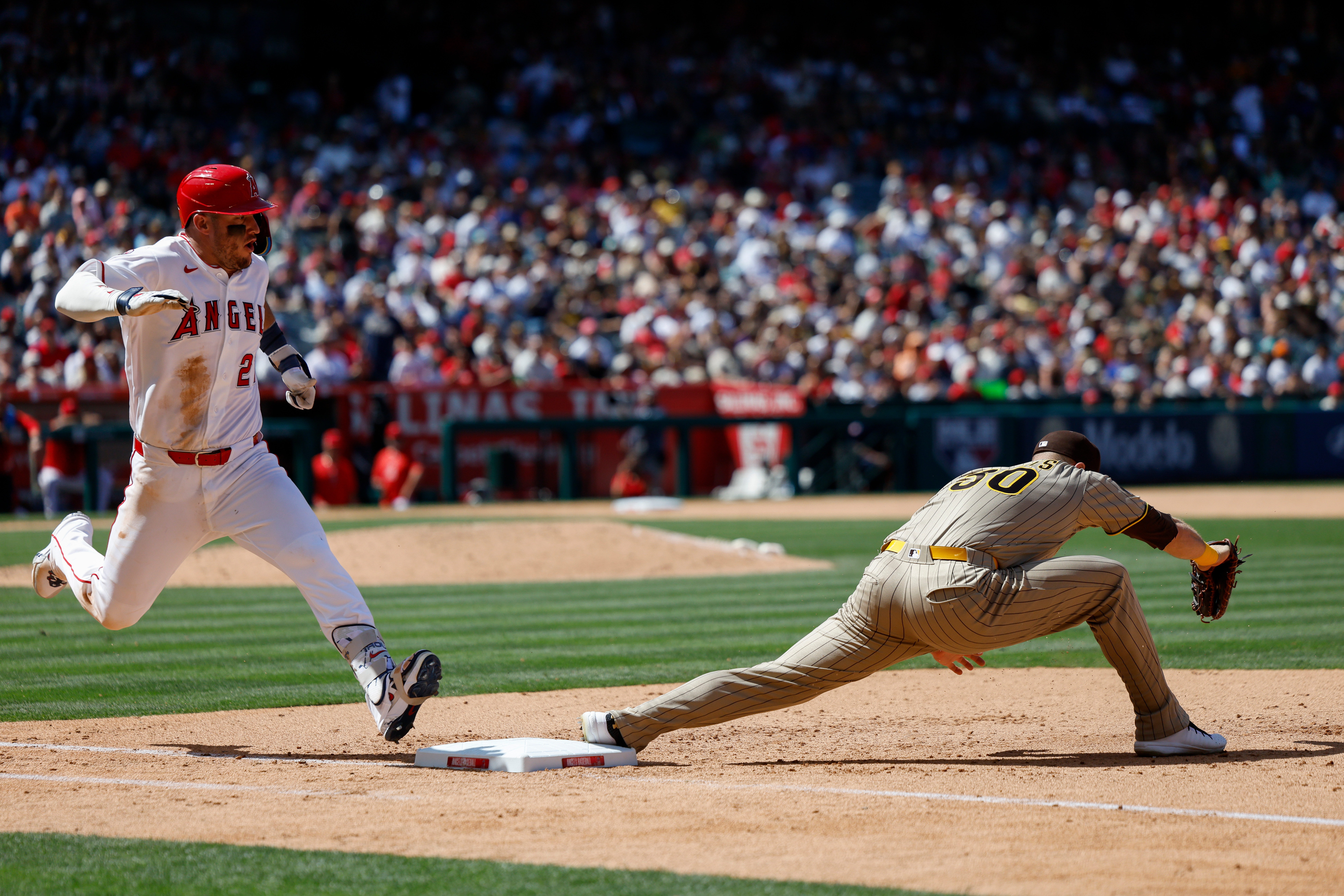Los Angeles Angels’ Mike Trout, left, runs to first base...