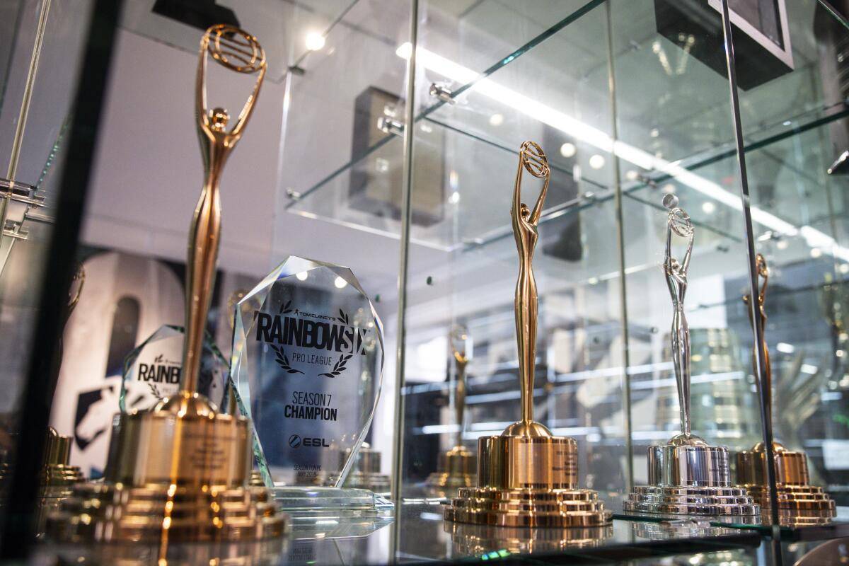 Team Liquid trophies in a display case while team members play World of Warcraft during the Race to World First (RWF) 