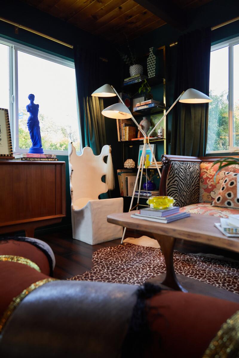 A living room with green walls, art and eclectic furnishings