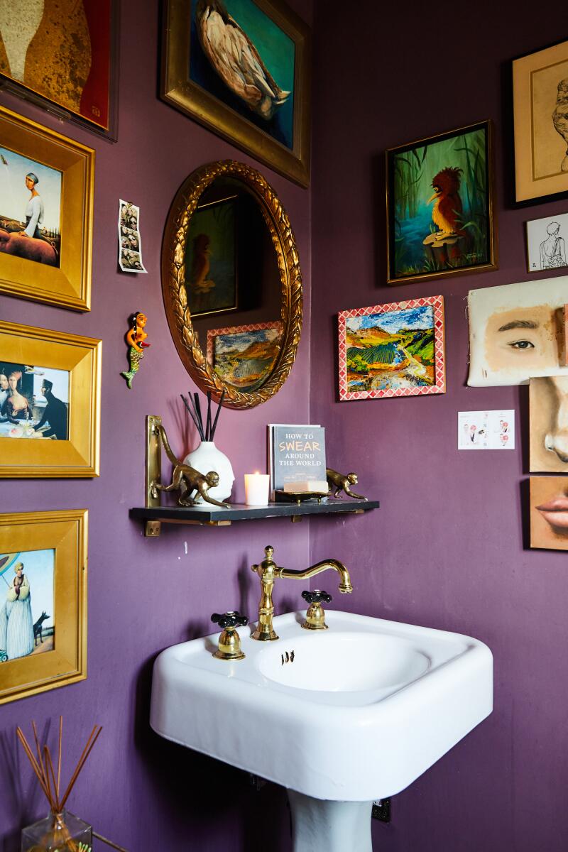 A purple bathroom with artworks hanging on the walls.
