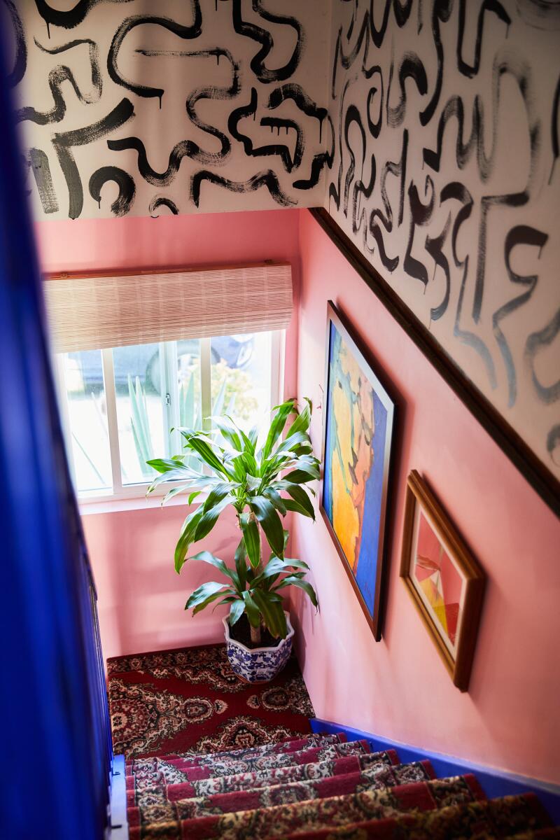 A staircase with pink walls leads to the downstairs.