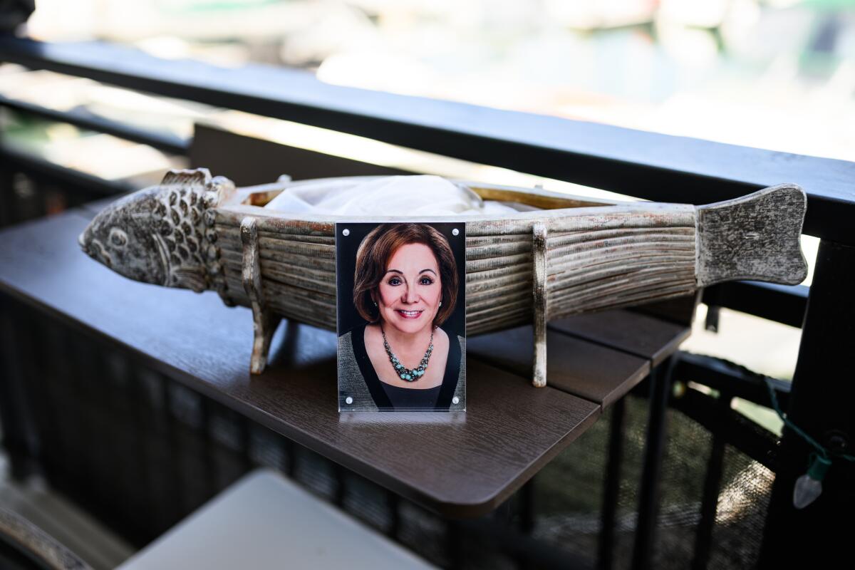 A photo of Lorraine Bird in front of a fish vase containing her ashes.