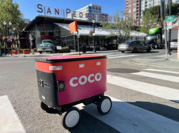 A Coco deliverybot crosses a street in front of San Pedro Square Market in downtown San Jose. The Santa Monica-based robotics company deployed 20 of the bots in downtown San Jose in April 2026. (Photo courtesy Coco Robotics)