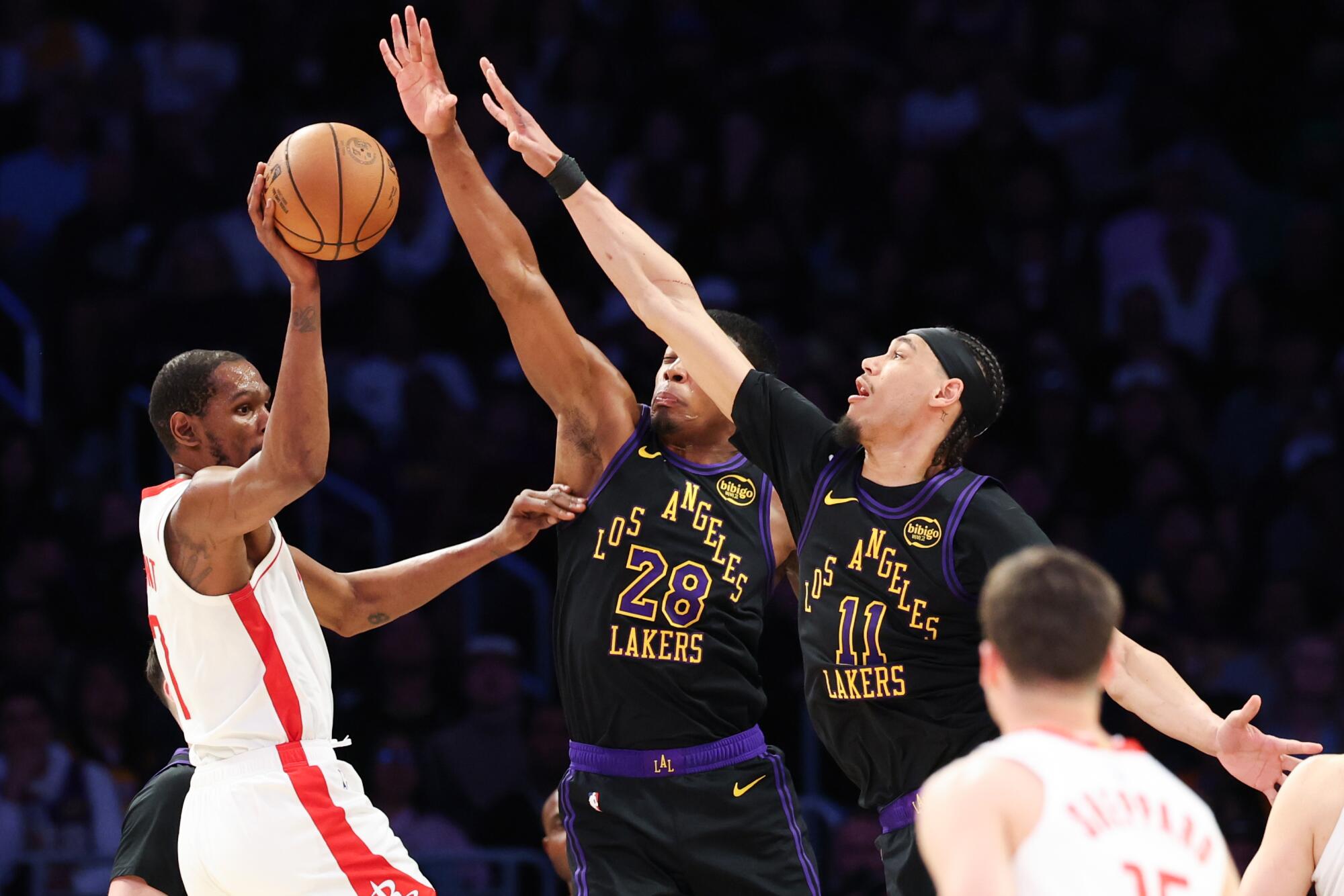 Houston forward Kevin Durant passes the ball under pressure from Lakers forward Rui Hachimura and center Jaxson Hayes.