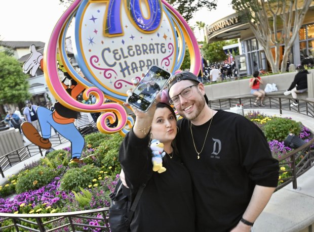 Maryanne Housholder and Nate Davis take a selfie in front of a 70th anniversary landmark along Buena Vista Street inside California Adventure at the Disneyland Resort in Anaheim, CA, on Tuesday, May 13, 2025￼. Disneyland is celebrating its 70th anniversary from May 16, 2025 through summer 2026... (Photo by Jeff Gritchen/MediaNews Group/Orange County Register via Getty Images)