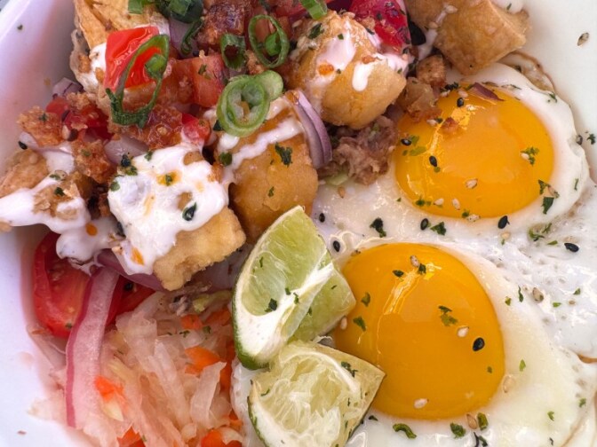A close up of Eggs on a bed of rice and veggies.
