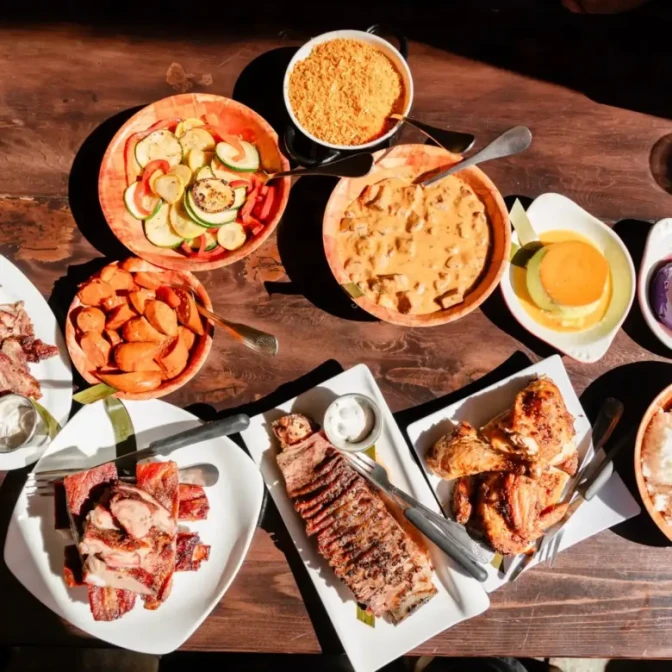 A top-down view of a wooden table covered in various Filipino dishes and BBQ.