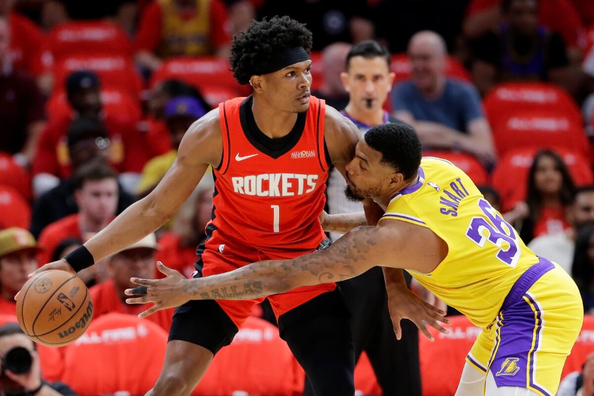 Rockets guard Amen Thompson, left, protects the ball as he dribbles while Lakers guard Marcus Smart reaches for a steal.
