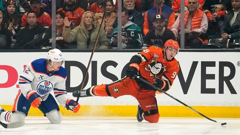 Anaheim Ducks defenseman Pavel Mintyukov, right, falls as he passes...