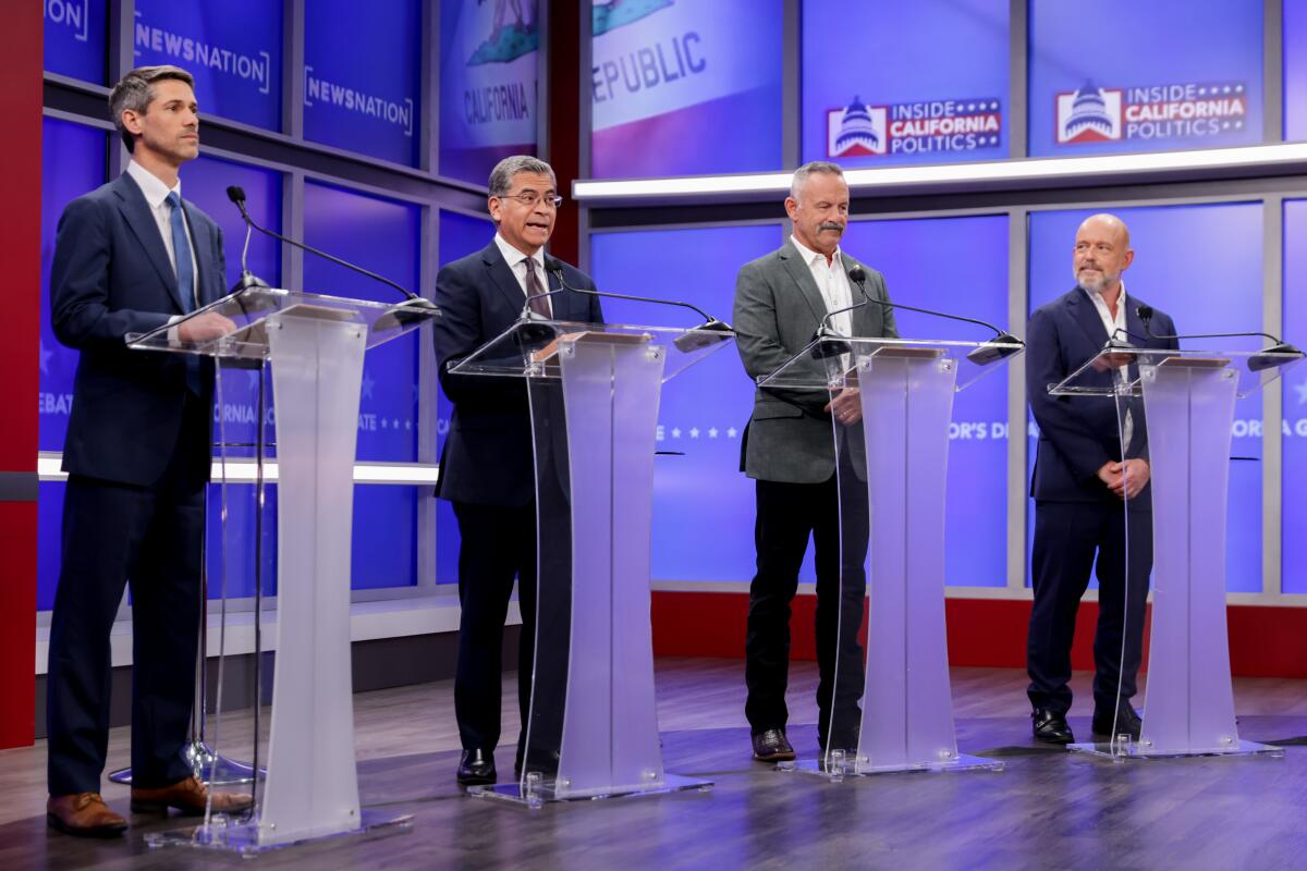 Four people stand behind four lecterns.