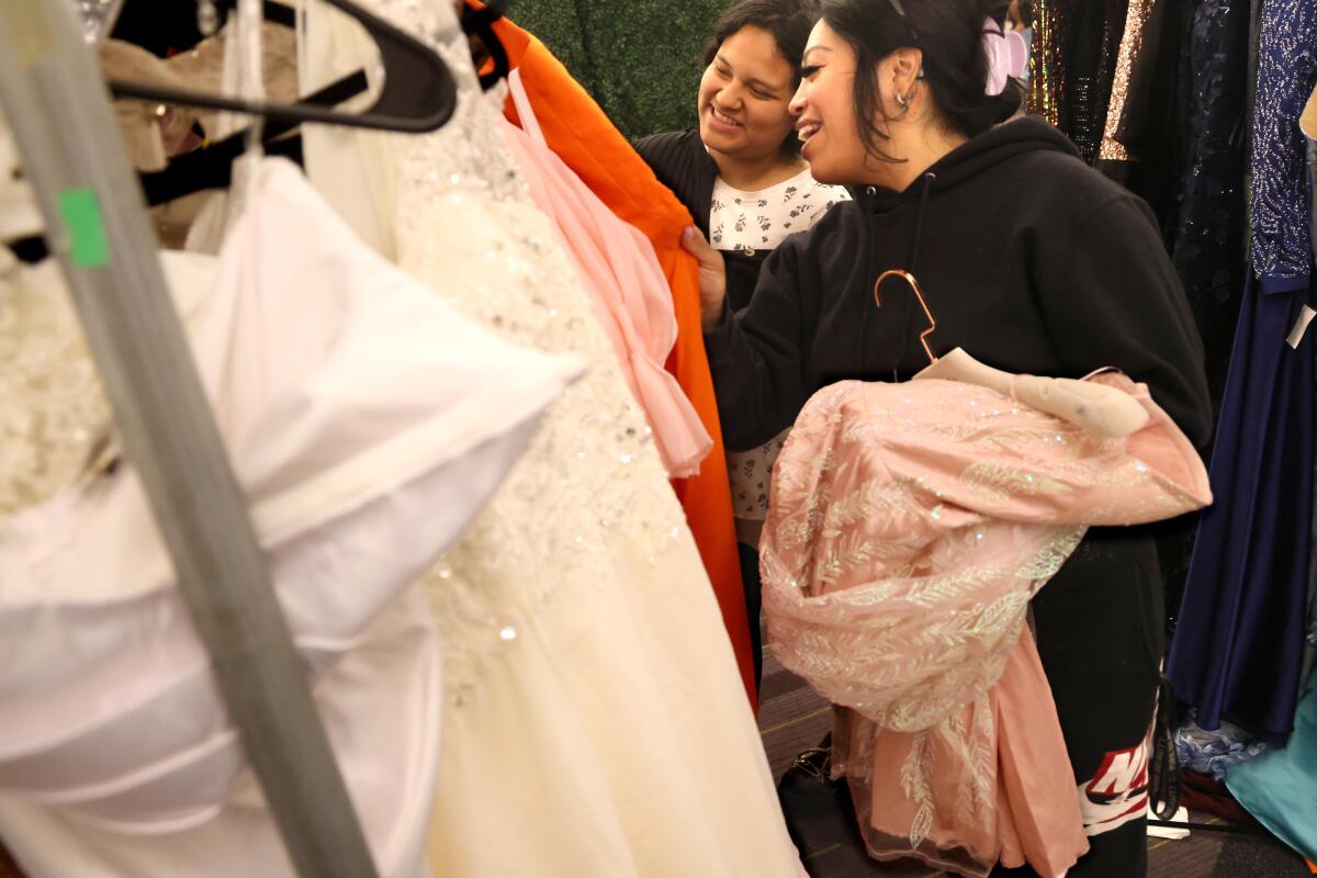 Volunteer Kali Rodriguez helps Ashley Luna find the perfect prom dress. 