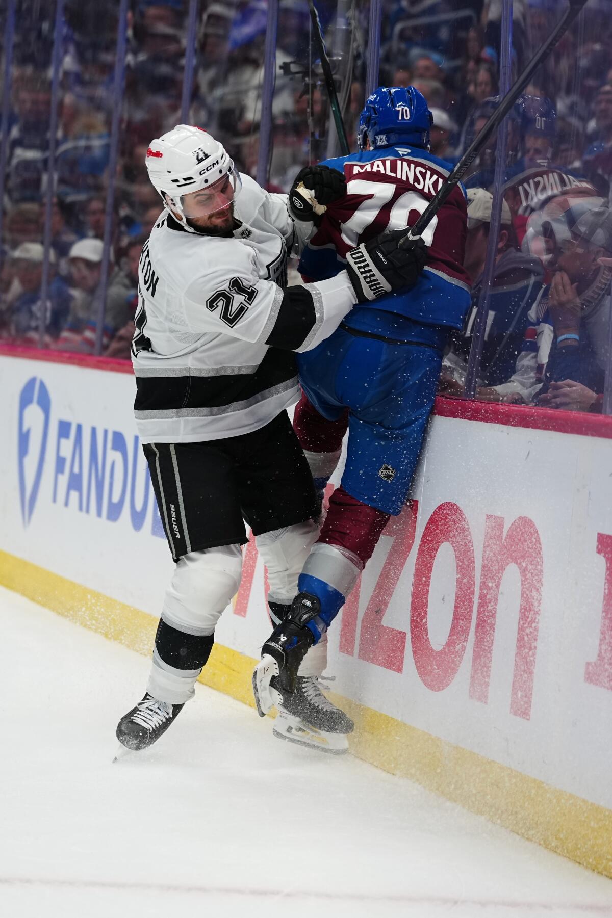 Kings center Scott Laughton, left, checks Avalanche defenseman Sam Malinski (70) into the boards during Game 2.
