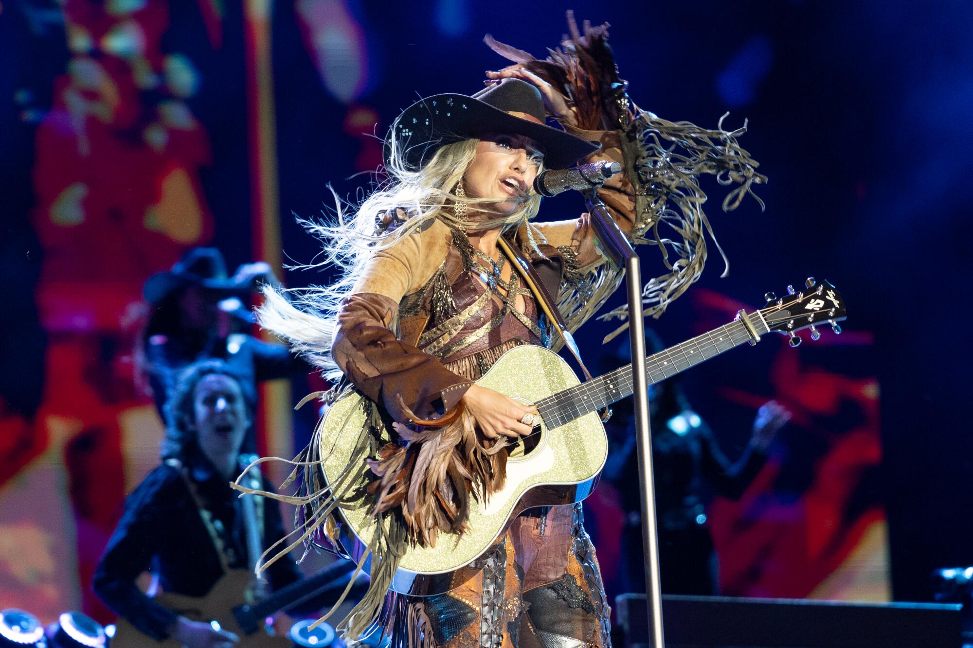 Lainey Wilson holds a guitar while singing at Stagecoach
